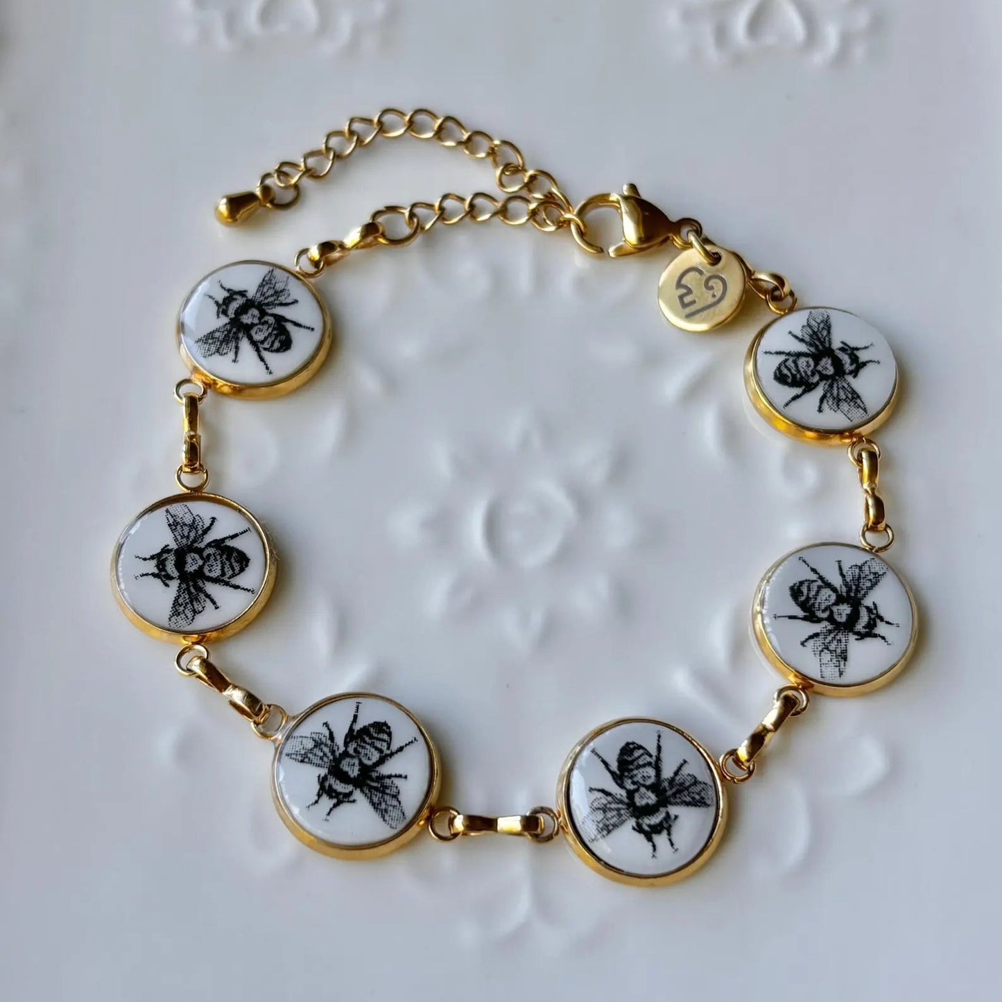 Bracelet with bee-themed charms on a textured white background