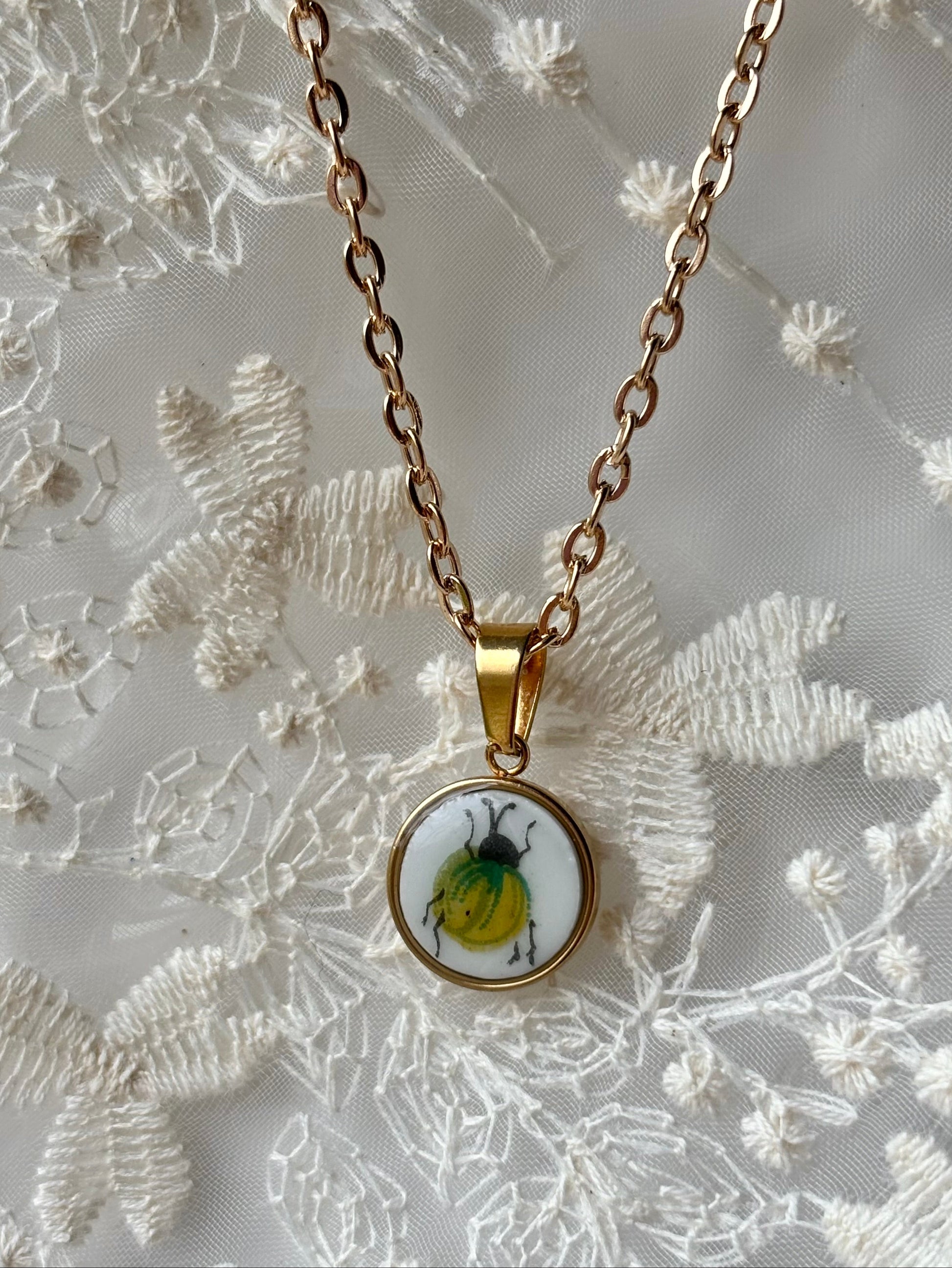 Necklace with a pendant featuring a beetle design on a floral background
