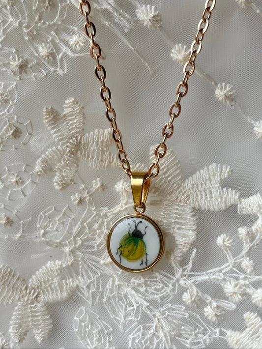 Necklace with a pendant featuring a beetle design on a floral background