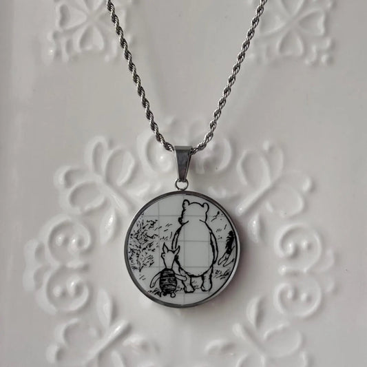 Necklace with a round pendant featuring a bear and rabbit design on an embossed white background.