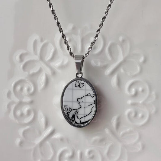 Silver pendant with a black and white design on a textured white background
