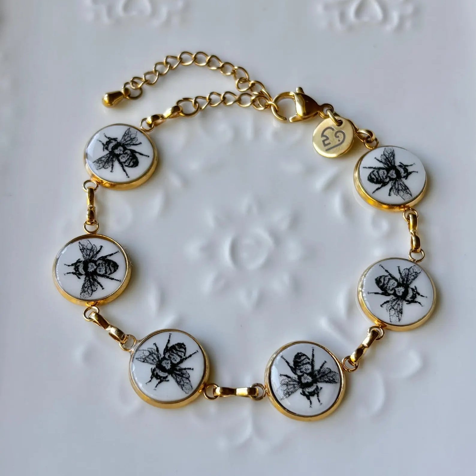 Bracelet with bee-themed charms on a textured white background