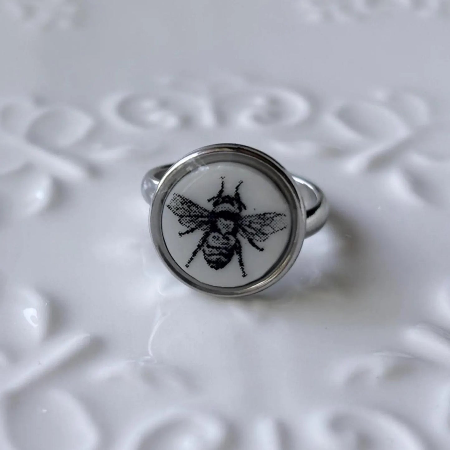 Ring with bee design on a textured white background