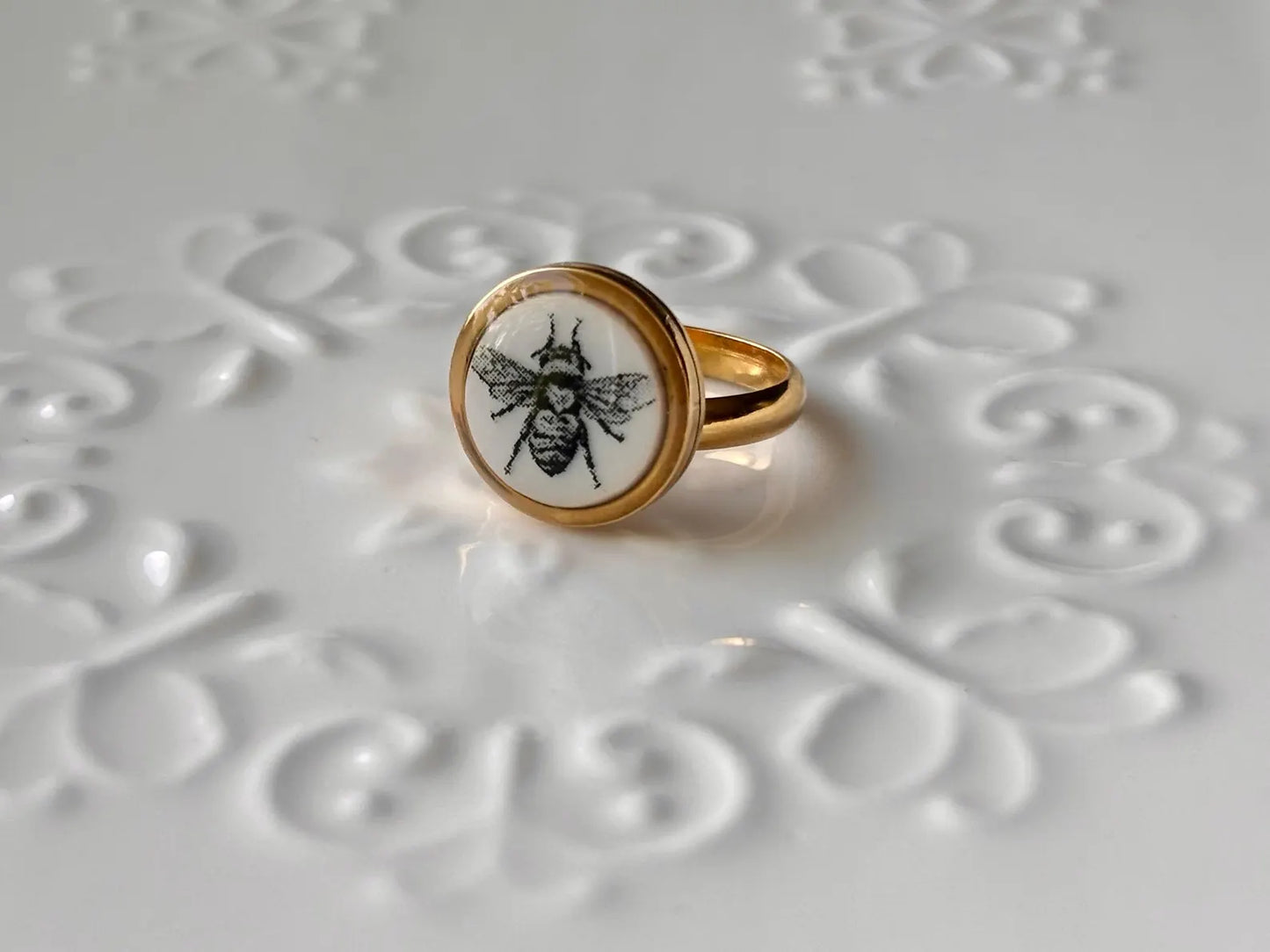 Gold ring with a bee design on an embossed surface