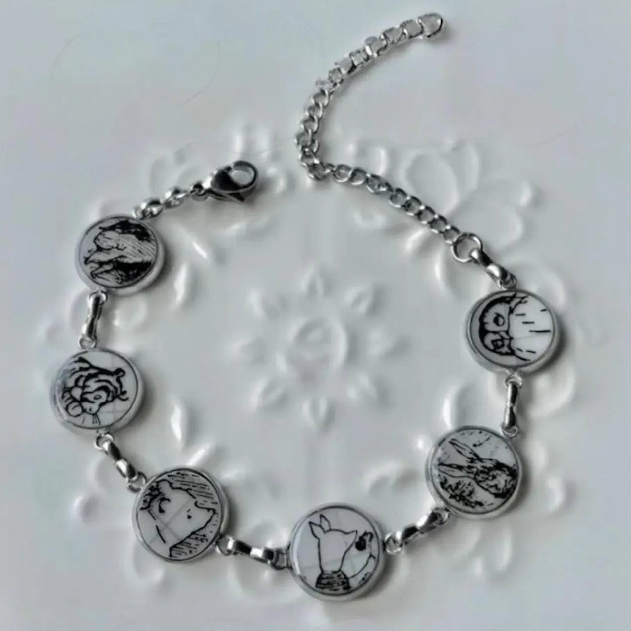 Silver bracelet with circular charms on a textured white background