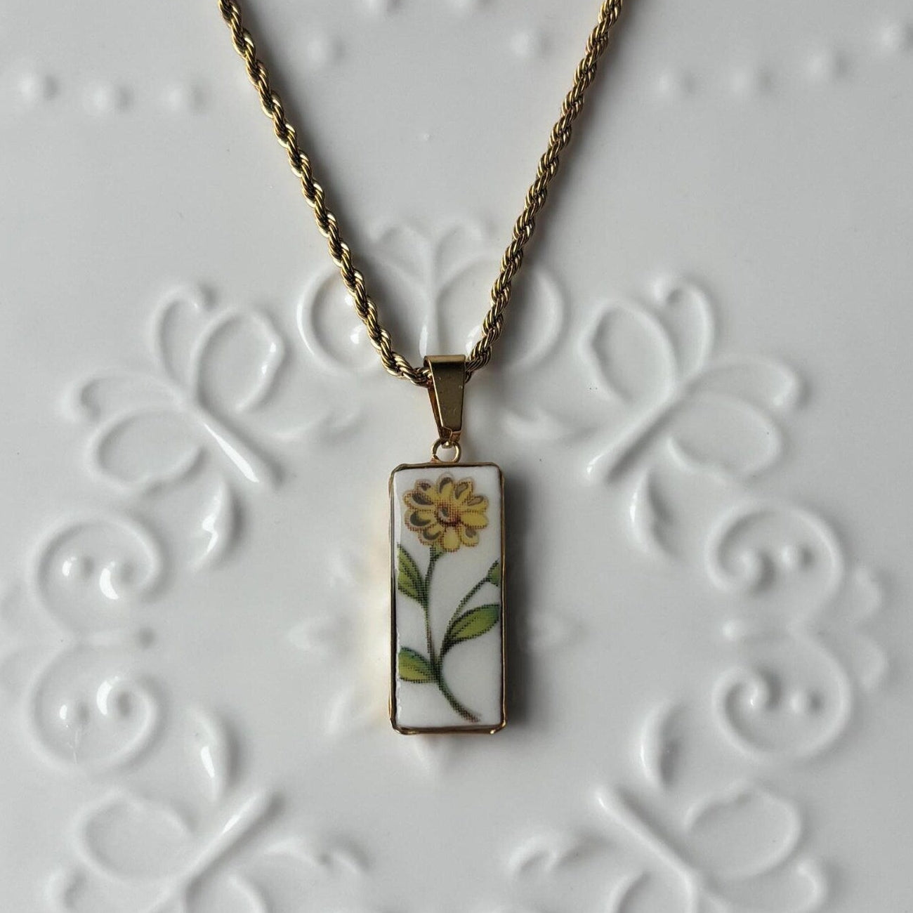 Necklace with a pendant featuring a floral design on a white textured background