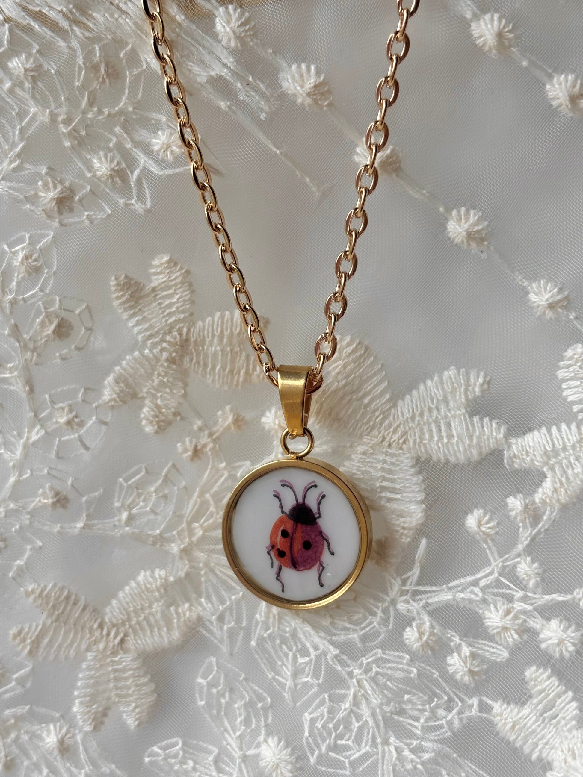 Necklace with a pendant featuring a ladybug design on a textured white background