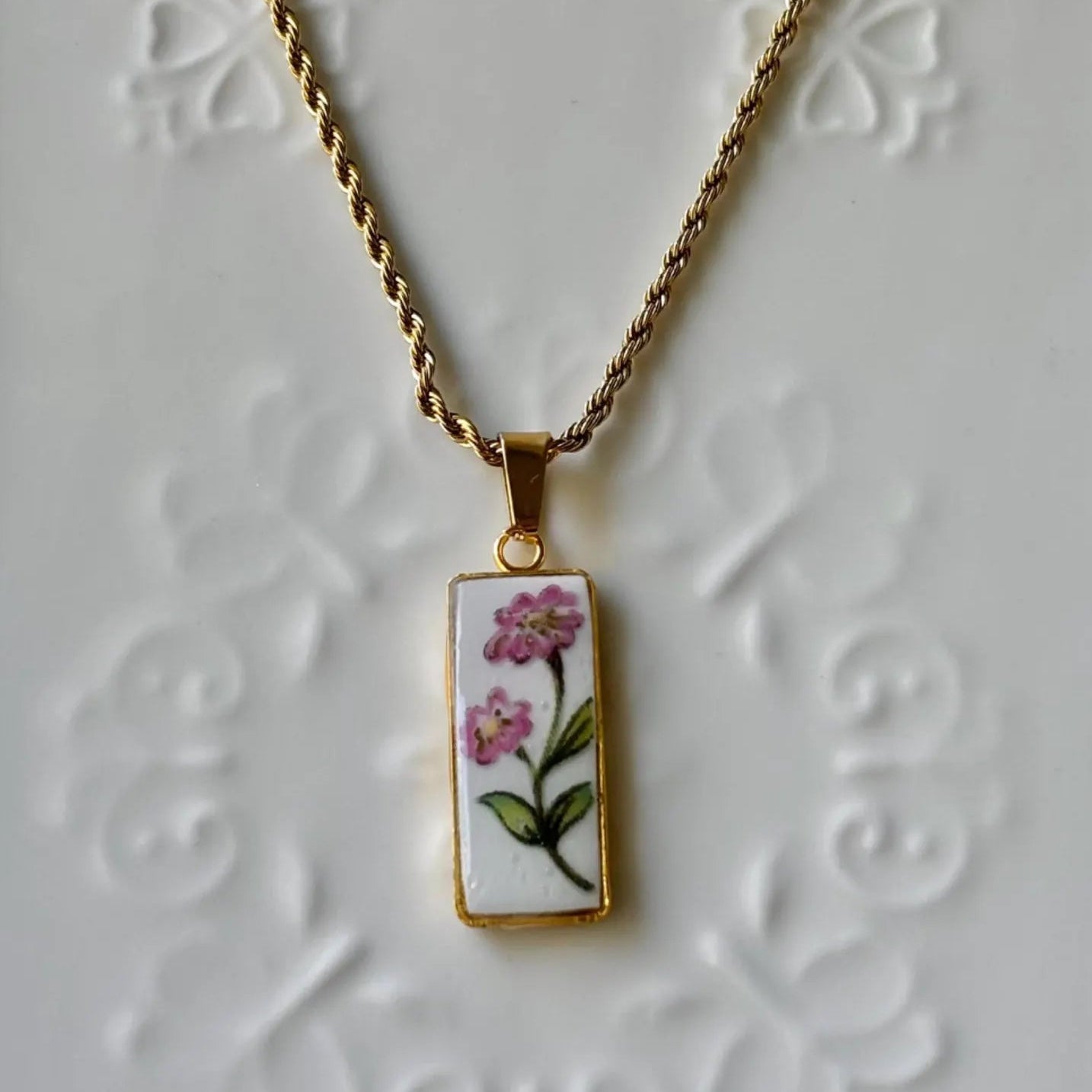 Necklace with a pendant featuring floral design on a textured white background