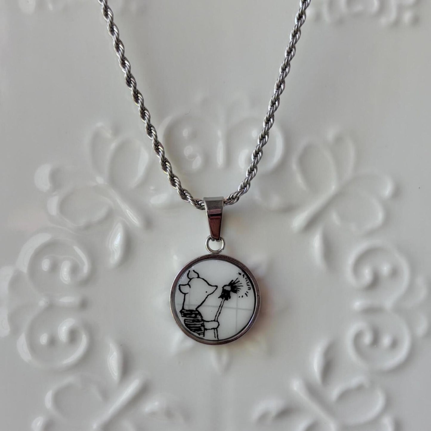 Necklace with a pendant featuring a black and white design on a textured gray background