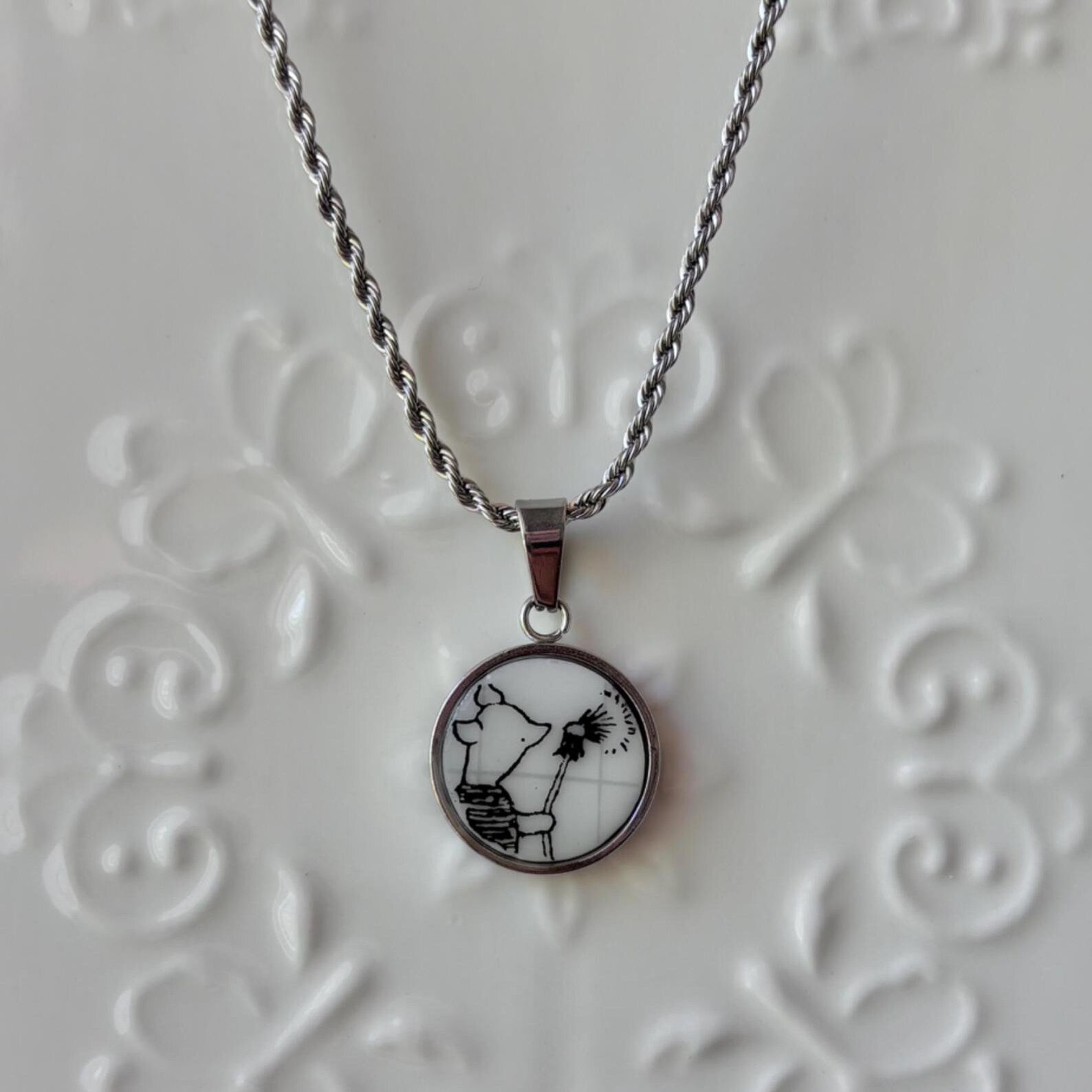 Necklace with a pendant featuring a black and white design on a textured gray background