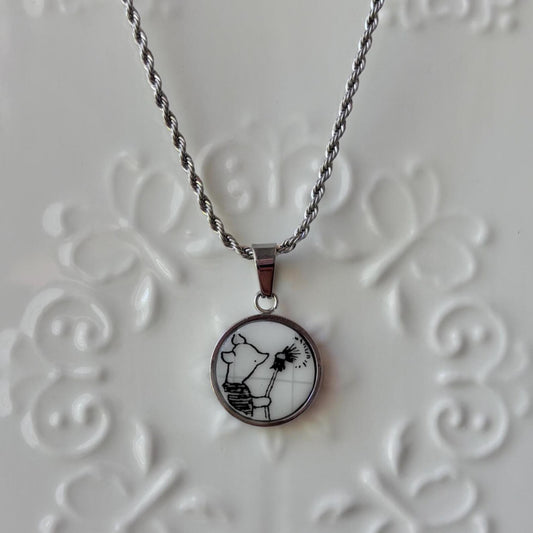 Necklace with a pendant featuring a black and white design on a textured gray background