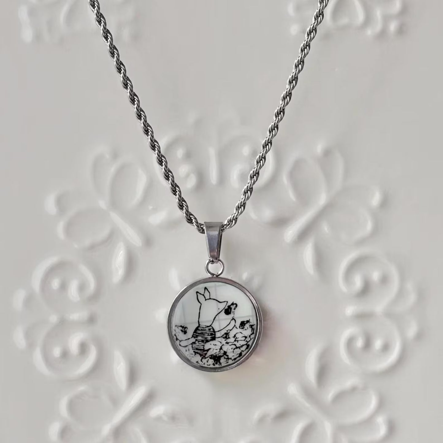 Necklace with a round pendant featuring a black and white design on a textured white background