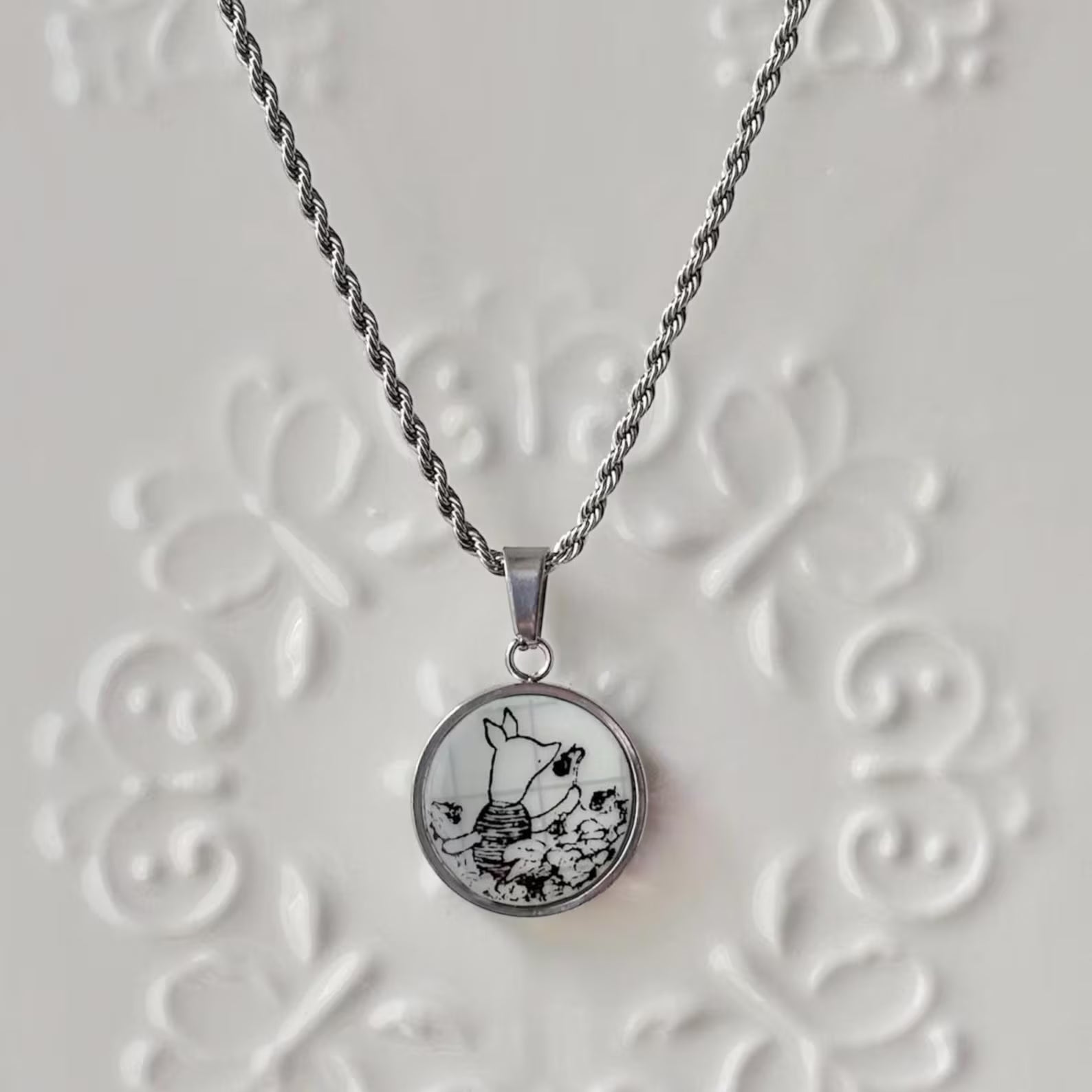 Necklace with a round pendant featuring a black and white design on a textured white background