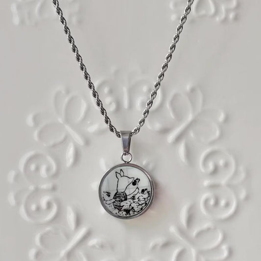 Necklace with a round pendant featuring a black and white design on a textured white background