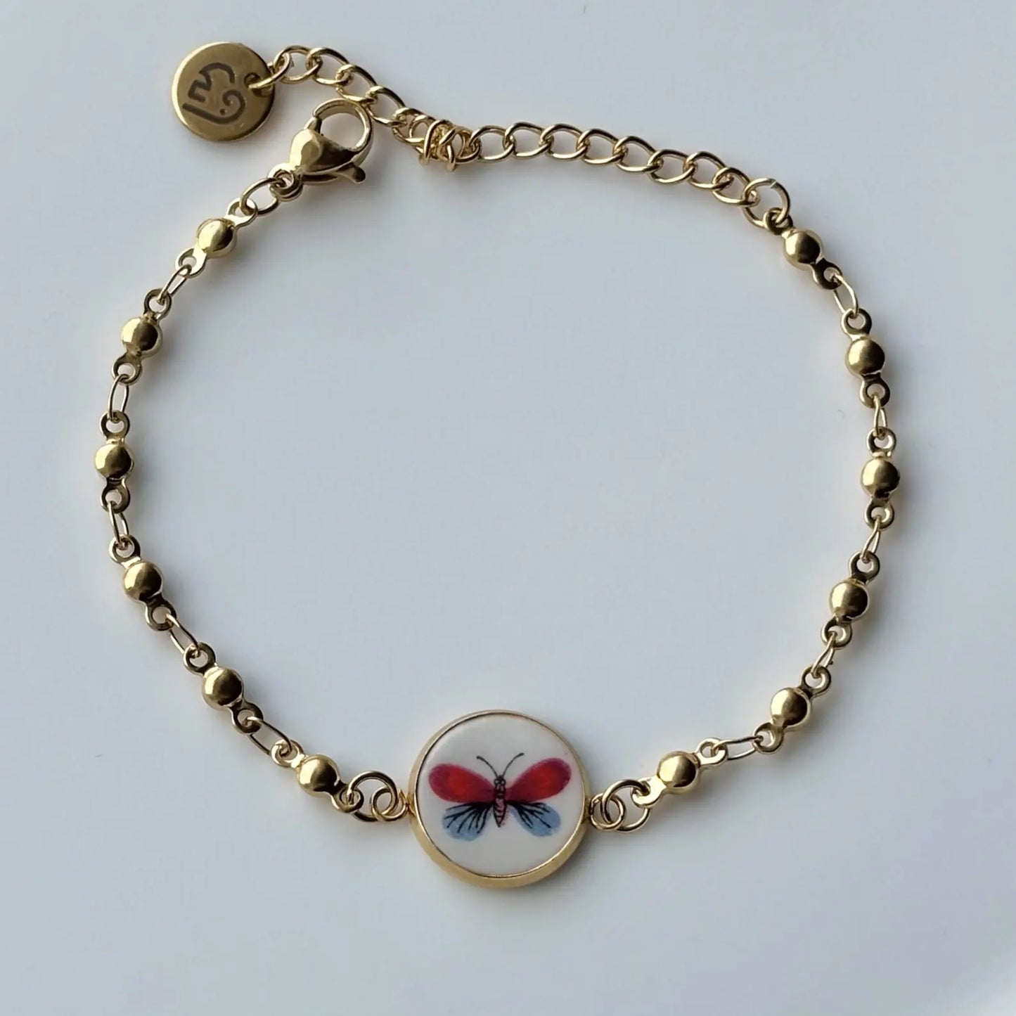 Gold bracelet with a butterfly charm on a white background