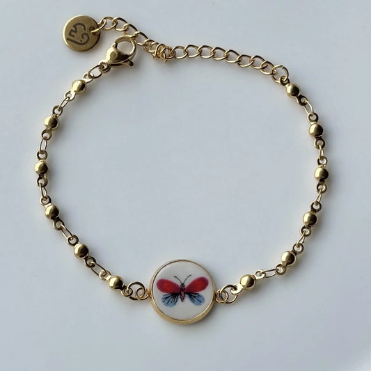 Gold bracelet with a butterfly charm on a white background