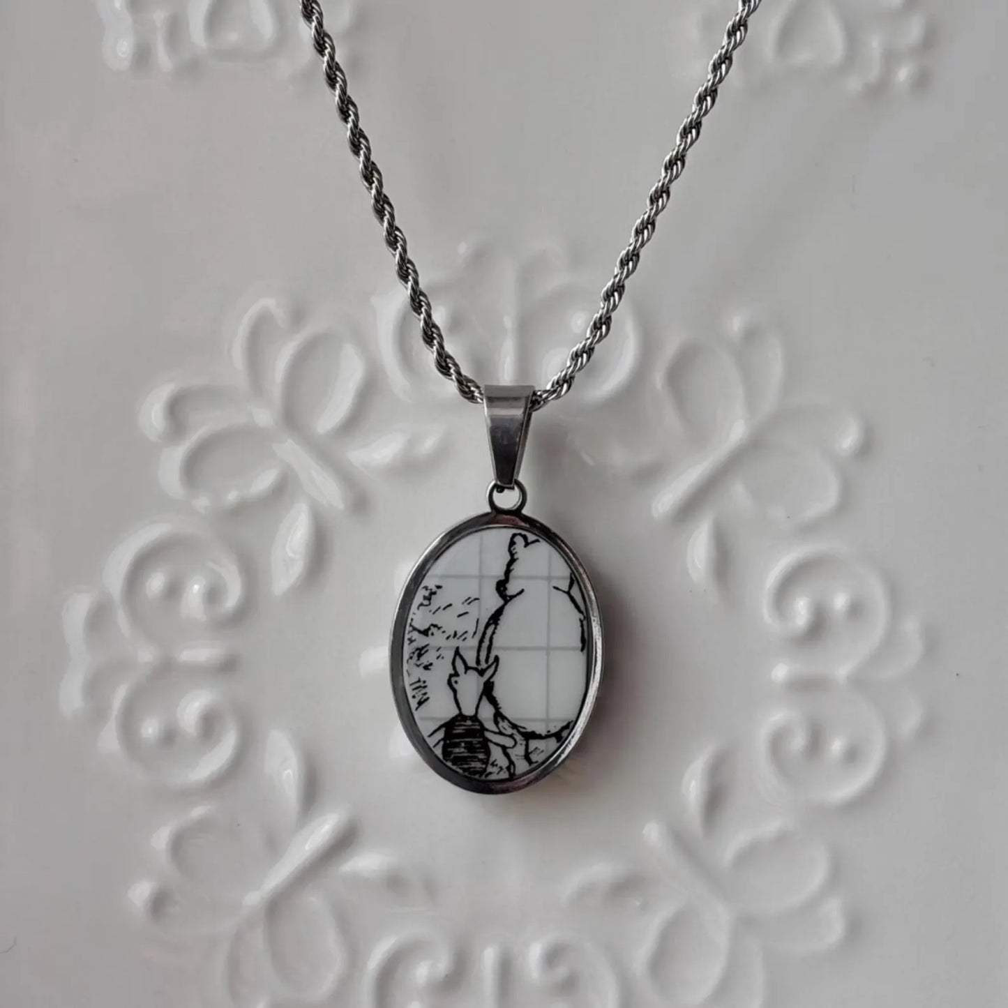 Necklace with a pendant featuring a bee design on an embossed gray background