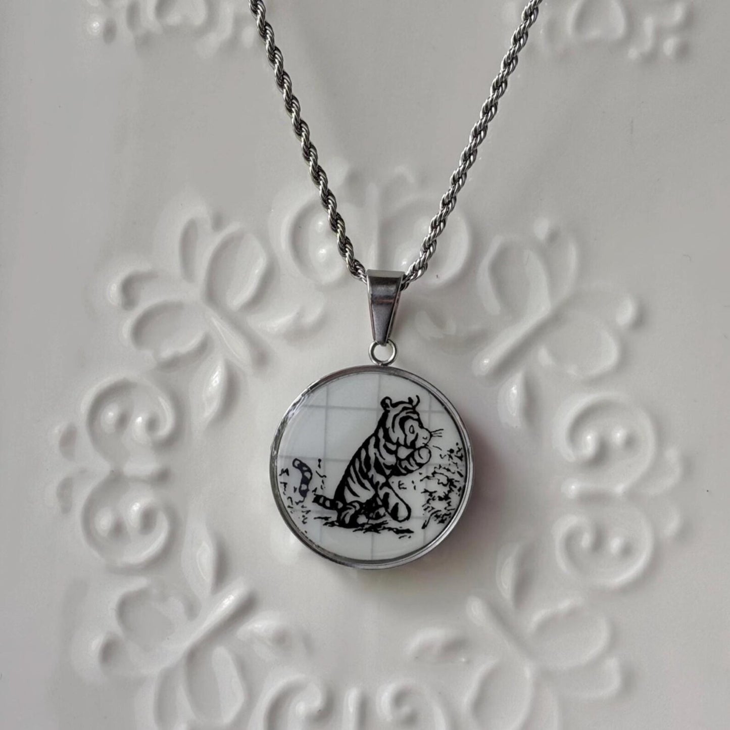Necklace with a pendant featuring a black and white tiger design on a textured white background