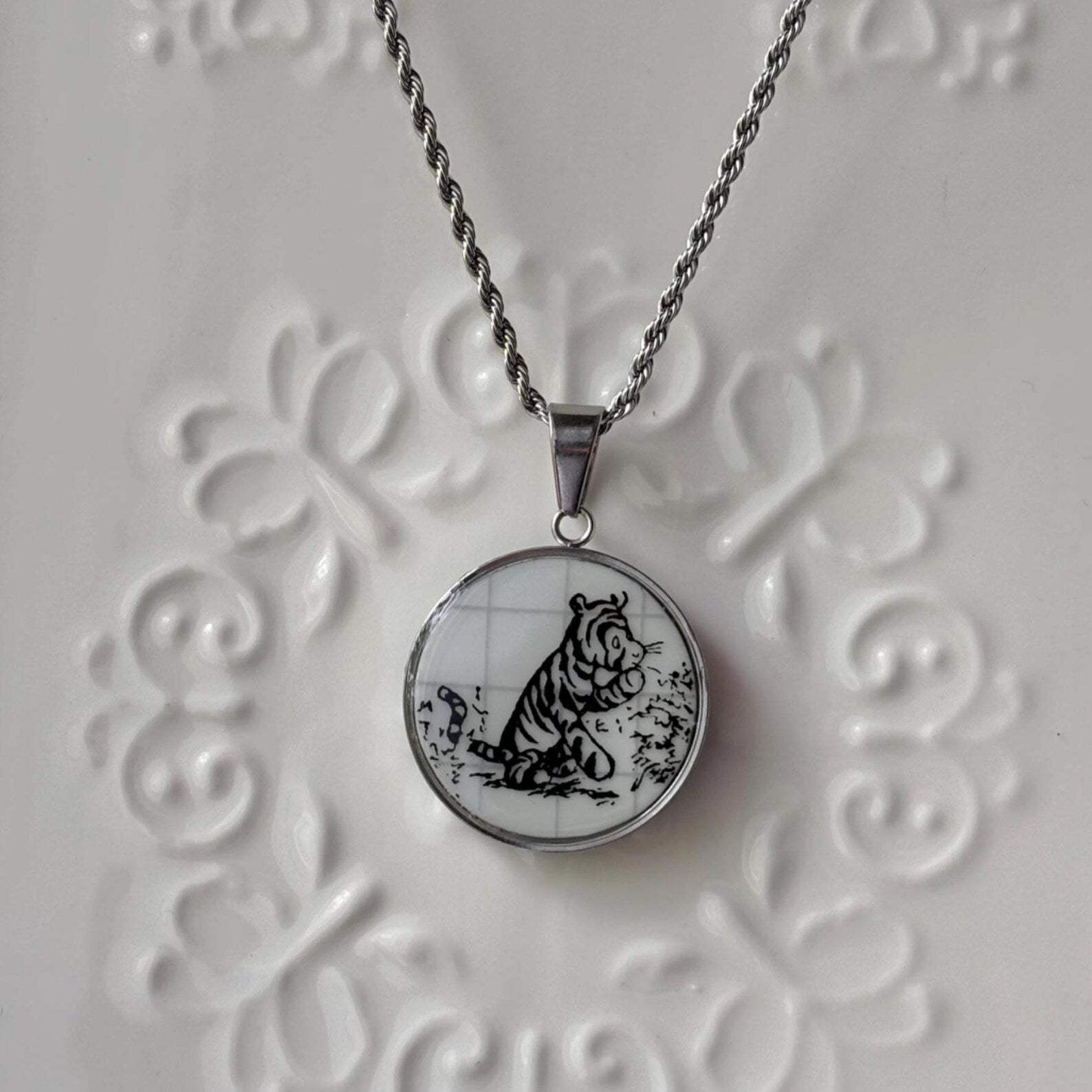 Necklace with a pendant featuring a black and white tiger design on a textured white background