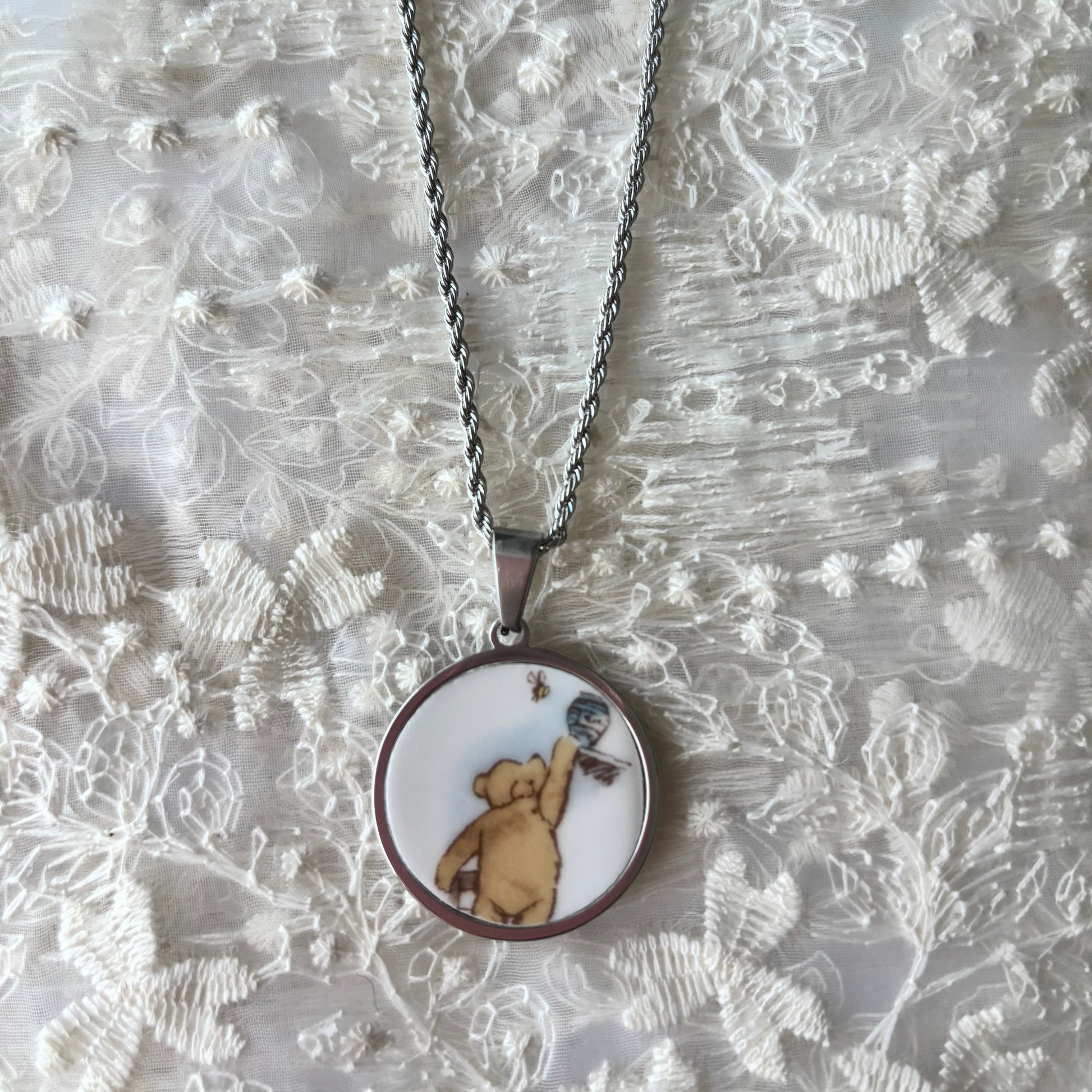 Necklace with a pendant featuring a bear design on a textured fabric background