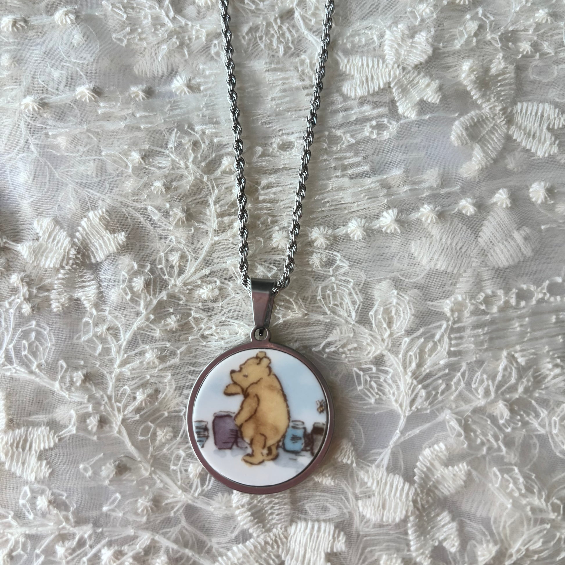 Necklace with a pendant featuring a cartoon bear design on a textured silver background
